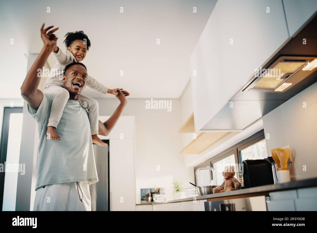 Dad dances with his daughter sitting on his shoulders. Father entertains and plays with his daughter in the morning. Happy moments shared between a si Stock Photo