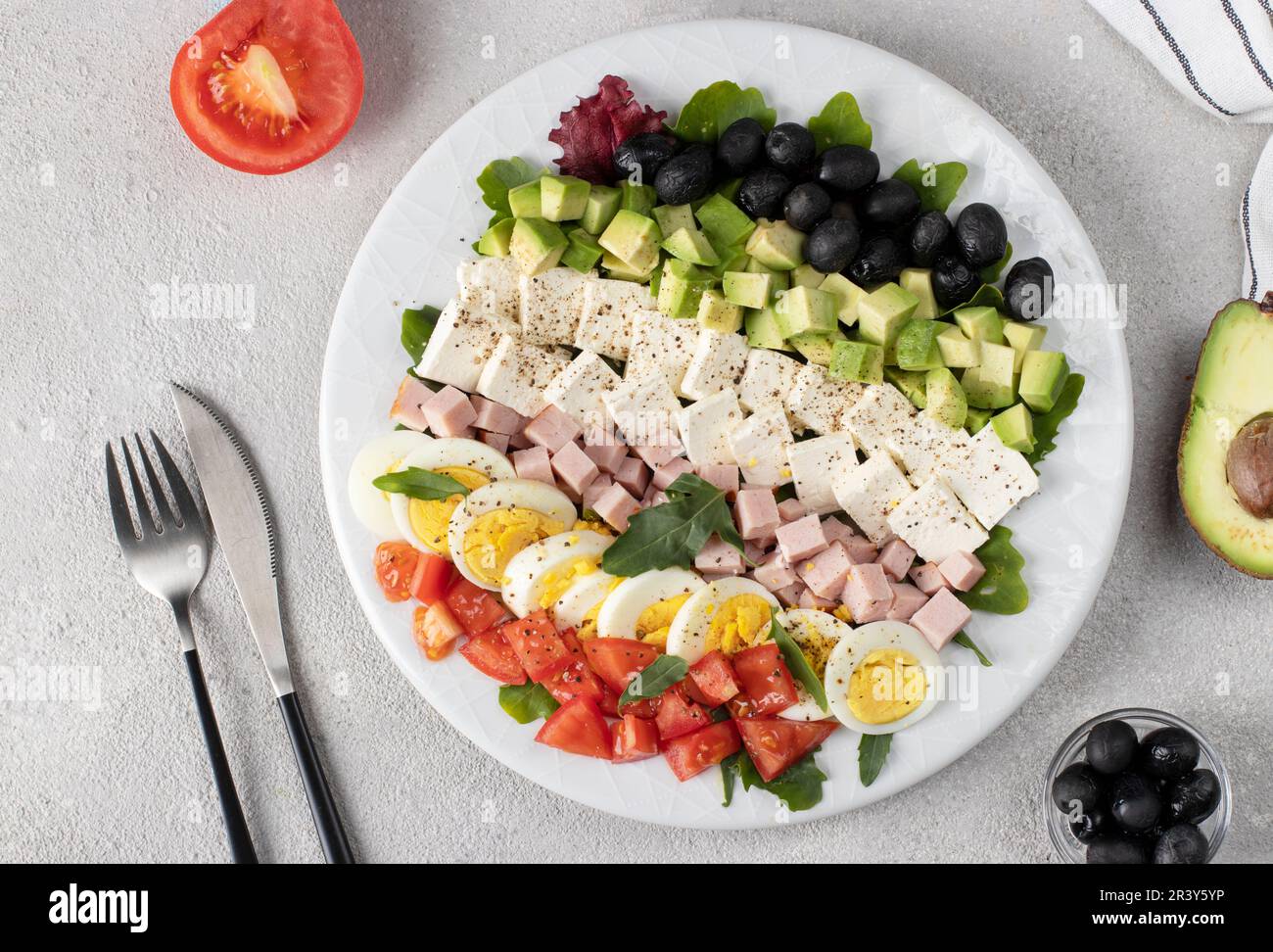 Healthy cobb salad with ham, feta cheese, avocado, tomato, black olives