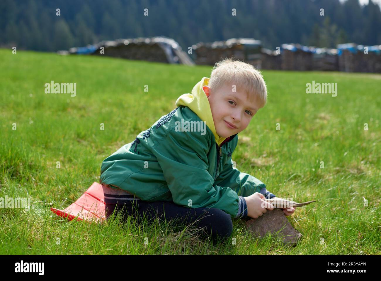 Fun teenager sits on hillside. Boy resting in mountains. School boy