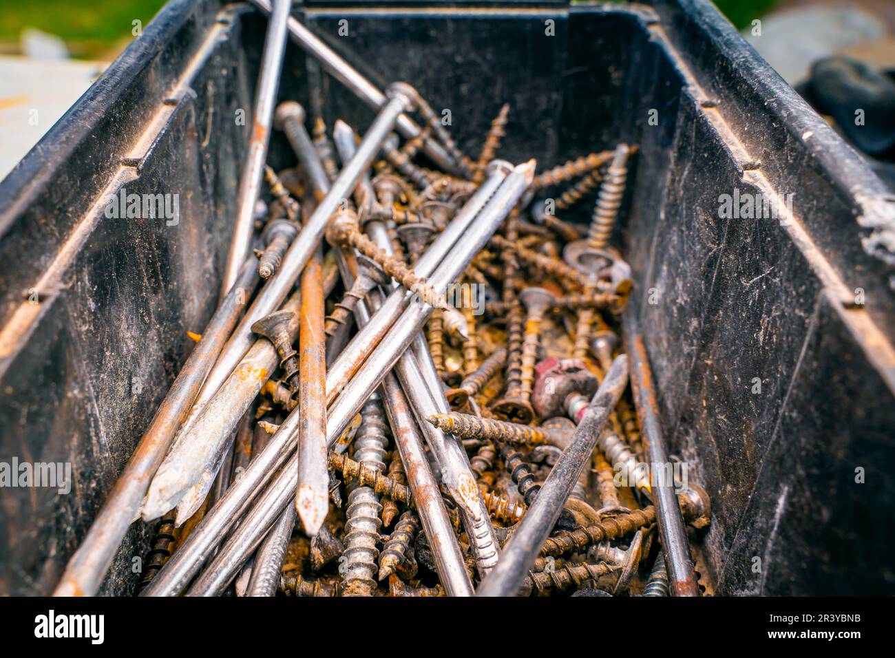 Old rusty nails and selftapping screws in a plastic container, close