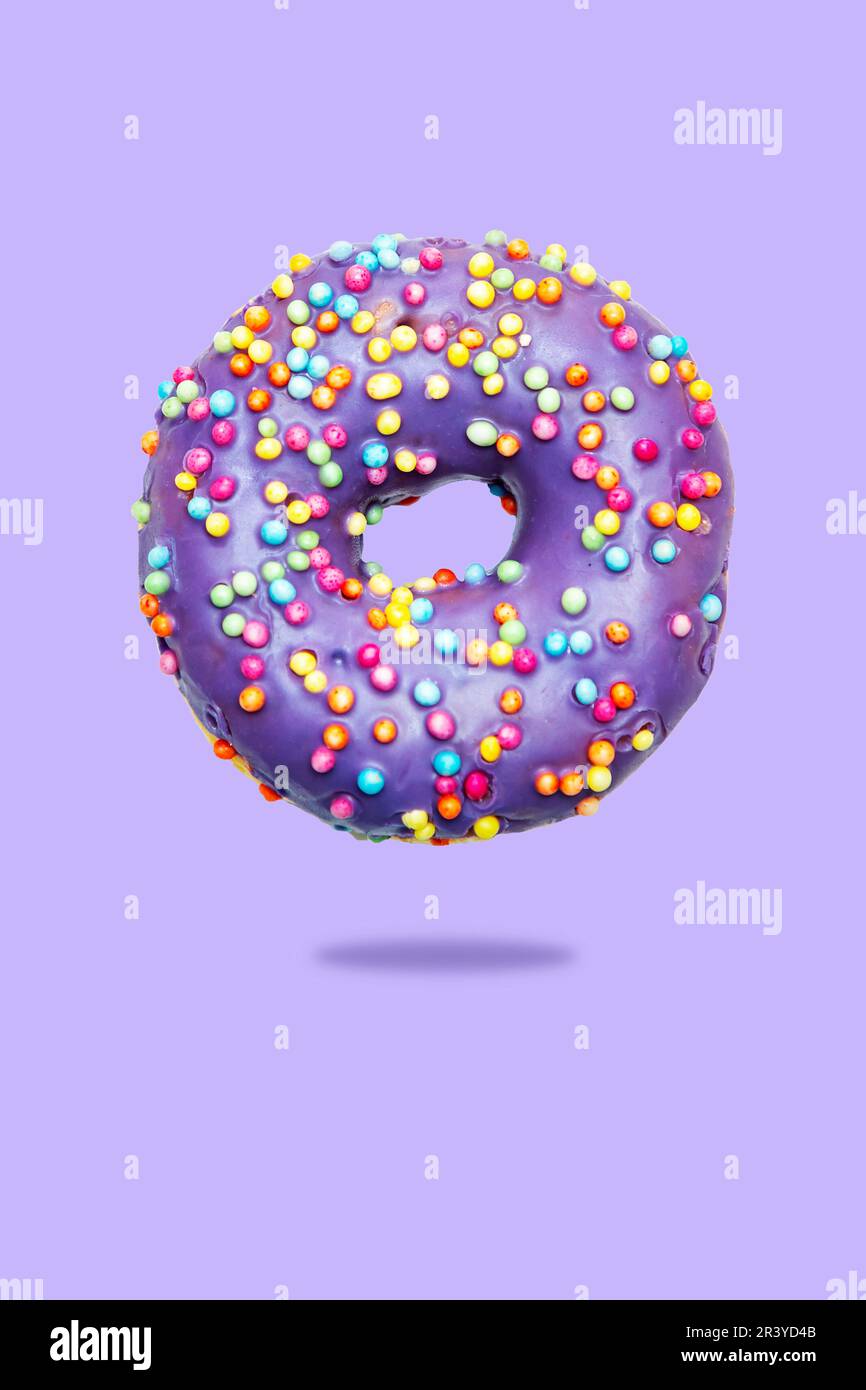 Donut with lilac glaze and sprinkles. Isolated on a lilac background ...