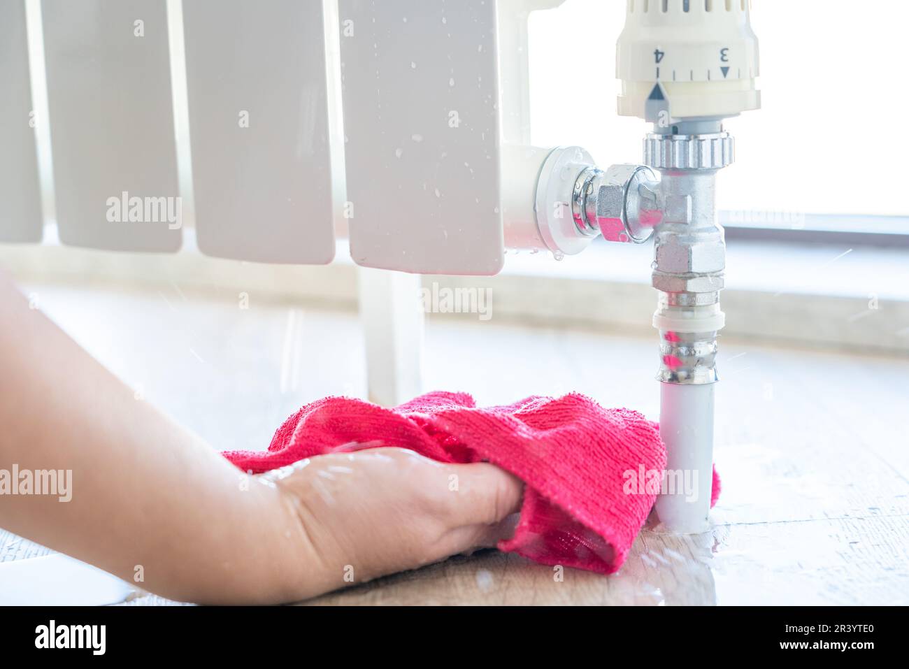 Female hand with rag cleaning water from heating radiator leak Stock