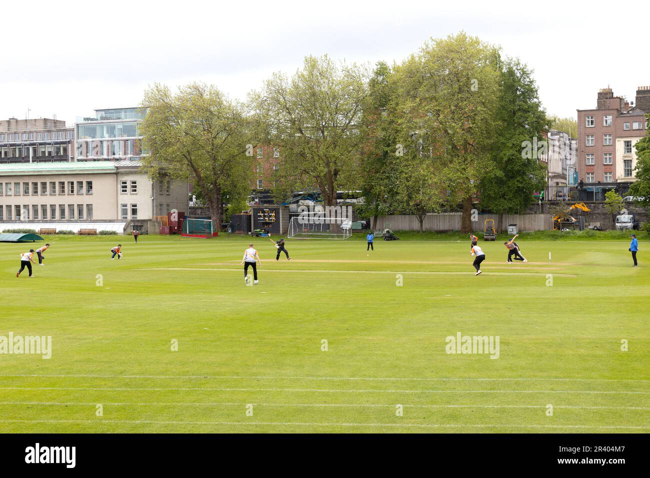 Young men playing cricket on a field at Trinity College in Dublin