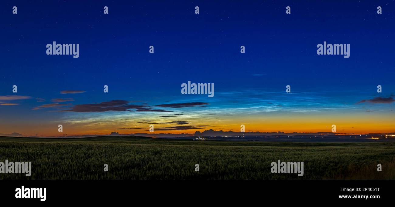 Wide angle view of noctilucent clouds over prairie field in Alberta, Canada. Stock Photo