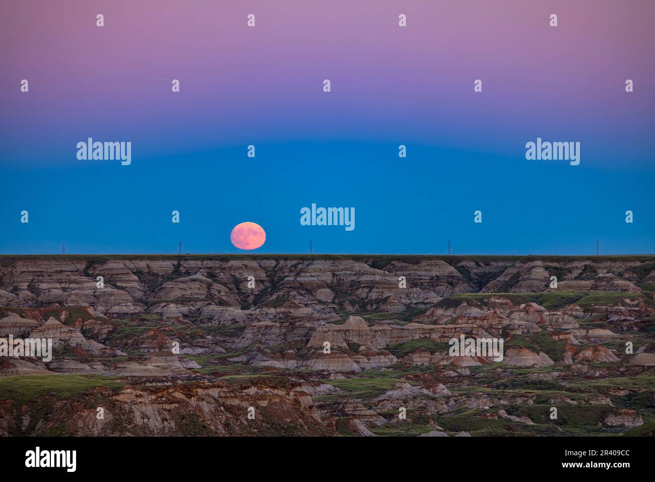 The rising supermoon of July 12, 2022 over the badlands of formations of Dinosaur Provincial Park, Canada. Stock Photo