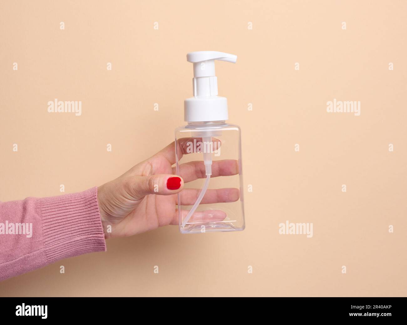 https://c8.alamy.com/comp/2R40AKP/female-hand-holds-empty-plastic-container-with-dispenser-for-liquid-products-soap-or-shampoo-on-beige-background-2R40AKP.jpg