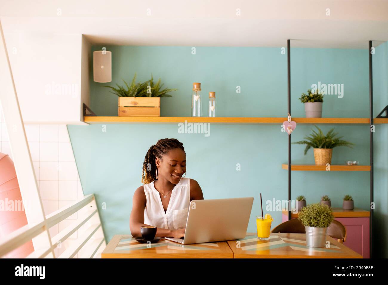 Pretty young black woman drinking coffee while working on laptop in the ...