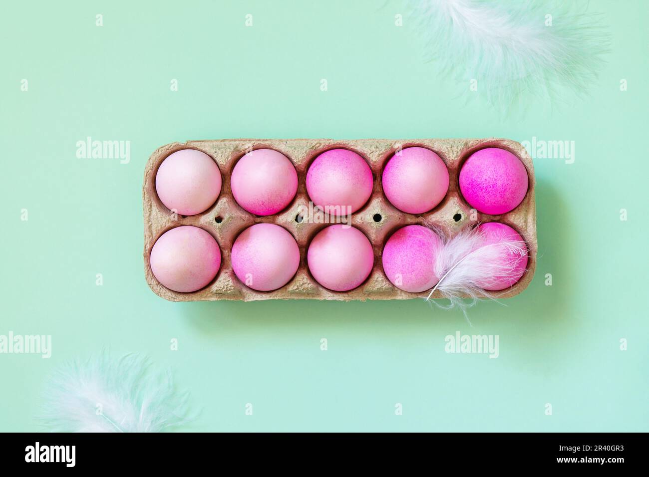 Minimal Easter concept. Easter elements, paper box with eggs in pink colors on pastel green background. Top view flat lay. Stock Photo
