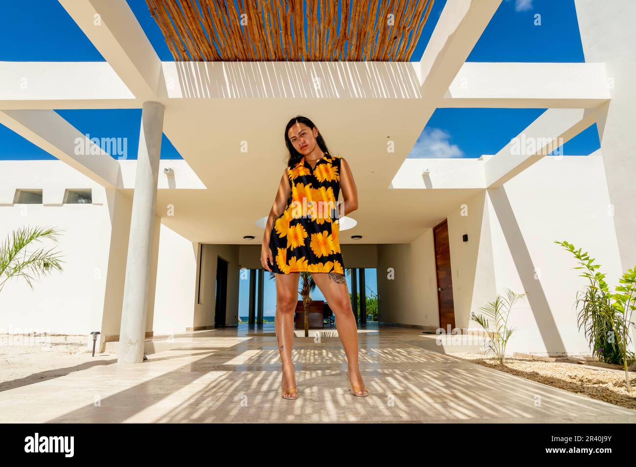 A Lovely Latin Model Poses Under A Bamboo Ceiling, Making Beautiful Shadows On The Tile Floor Stock Photo