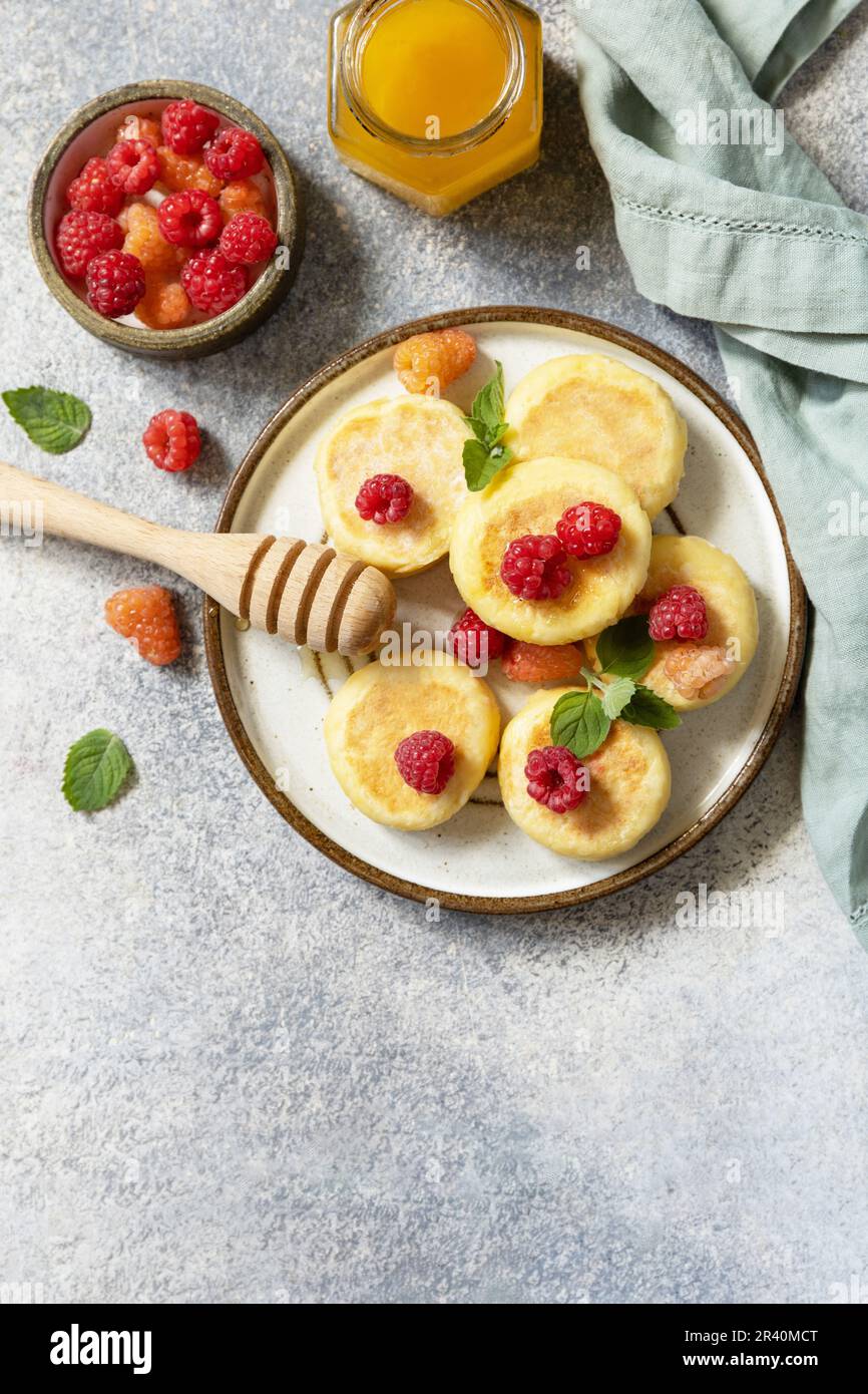 Homemade cottage cheese pancakes gluten free (syrniki, curd fritters) with berries on a stone background. Ricotta pancakes, morn Stock Photo