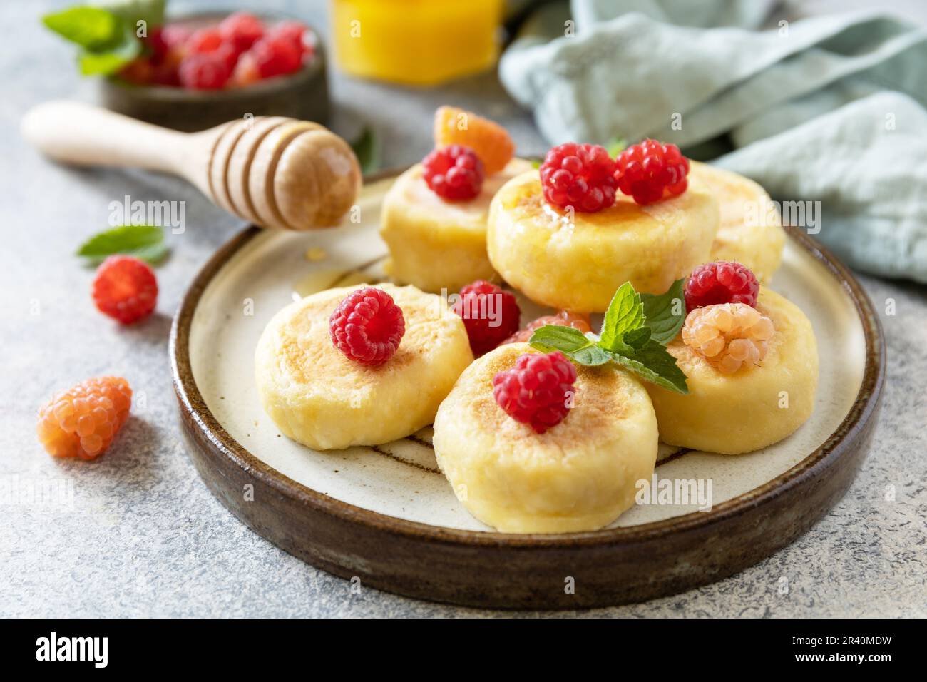 Homemade cottage cheese pancakes gluten free (syrniki, curd fritters) with berries on a stone background. Ricotta pancakes, morn Stock Photo