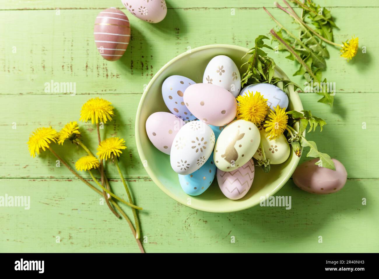 Happy Easter Holidays. Handmade Easter colorful eggs and spring flowers dandelions on a rustic wooden table. Easter composition. Stock Photo