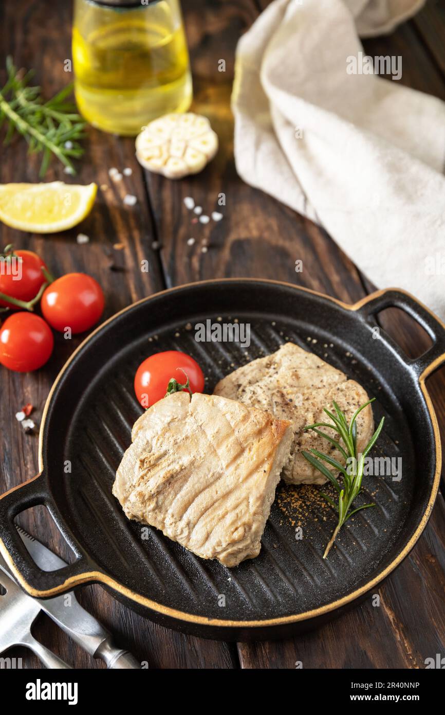 Cooked juicy tuna steak with spices, tomatoes and rosemary on a stone