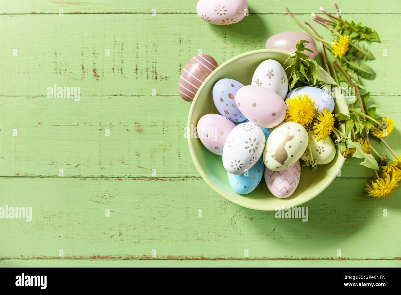 Happy Easter Holidays. Handmade Easter colorful eggs and spring flowers dandelions on a rustic wooden table. Easter composition. Stock Photo