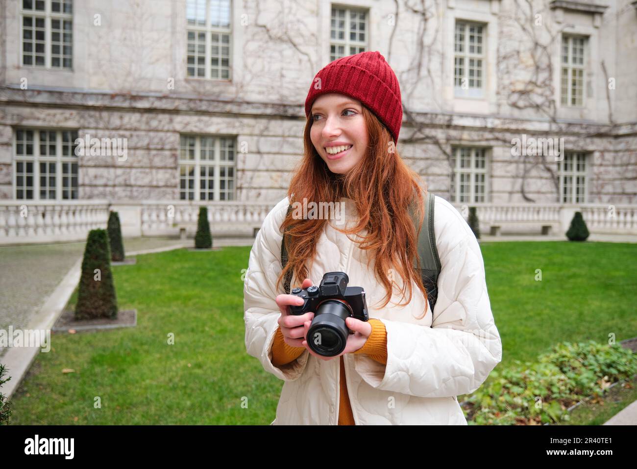 Redhead girl photographer takes photos on professional camera outdoors ...
