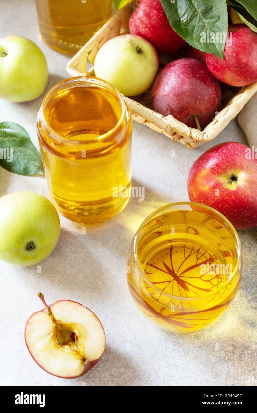 Apple juice in a glass and fresh apples on a stone tabetop. Autumn