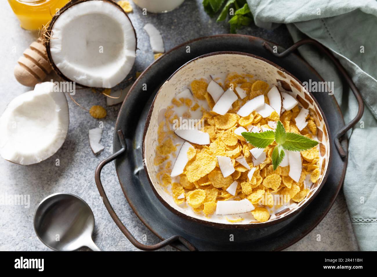 Summer vegan breakfast. Cereal granola breakfast flakes with coconut non-dairy alternative milk and fresh coconut slices on a st Stock Photo