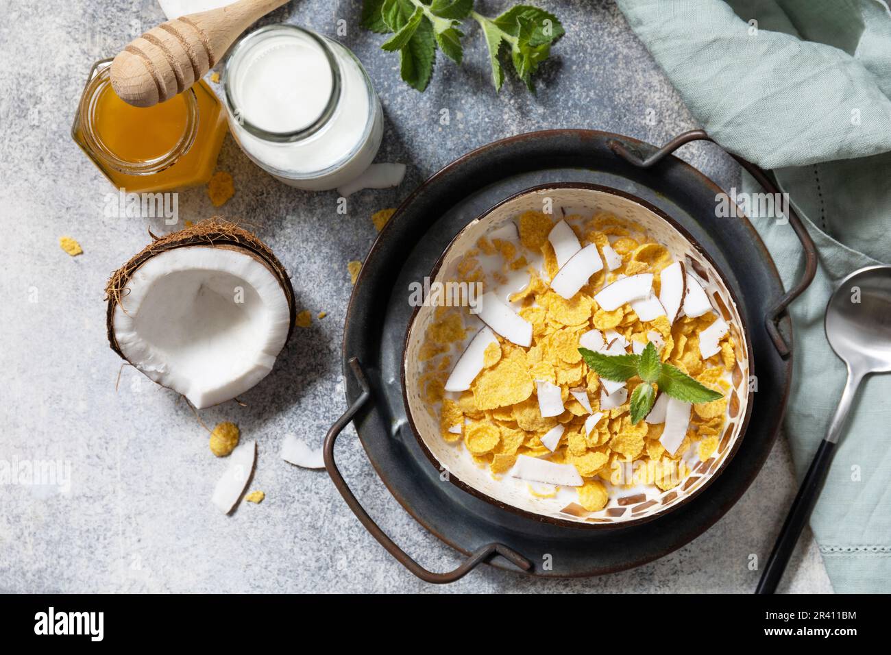 Summer vegan breakfast. Cereal granola breakfast flakes with coconut non-dairy alternative milk and fresh coconut slices on a st Stock Photo