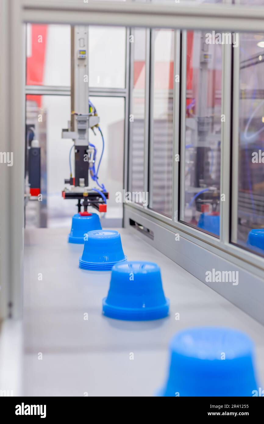 Pots on conveyor belt of plastic injection molding machine with robotic ...