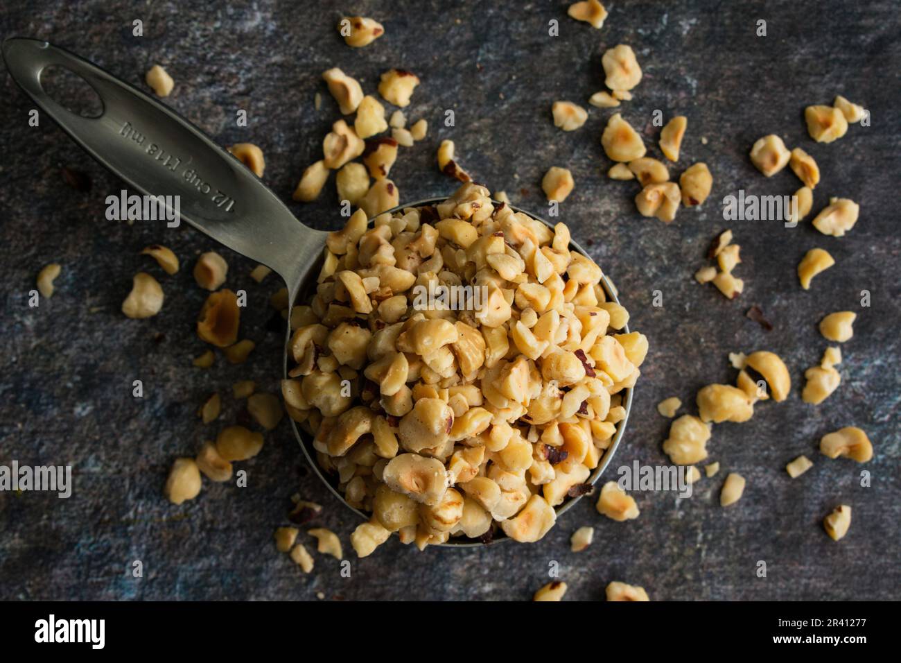 Toasted Hazelnuts in a Stainless Steel Measuring Cup Closeup side