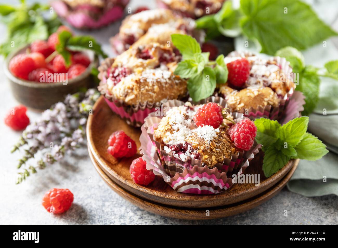 Healthy dessert. Vegan gluten-free pastry. Oatmeal banana muffins with raspberry and coconut flakes on a stone table. Stock Photo
