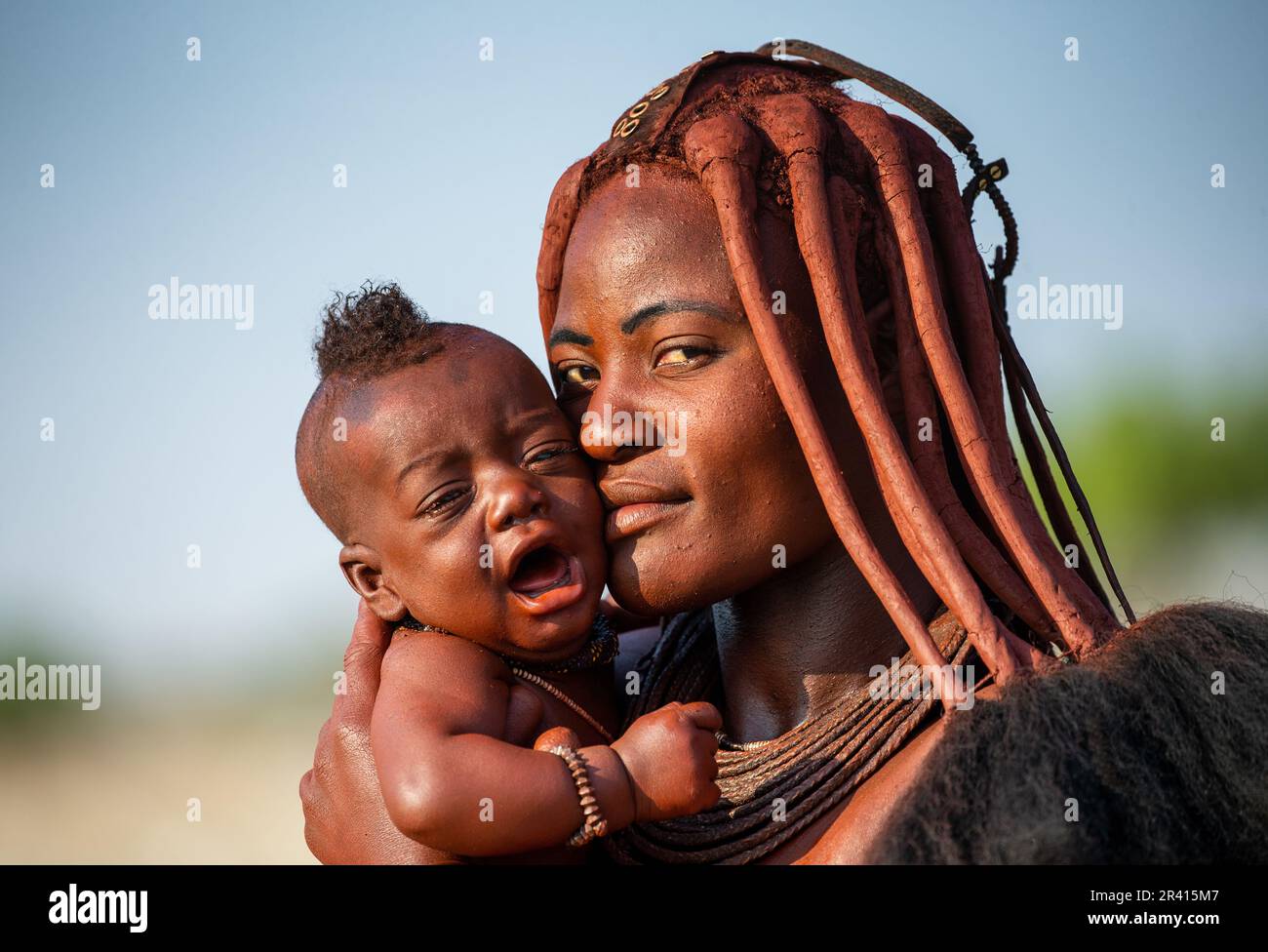 Portrait of a young woman of the Himba tribe with a small child in her ...