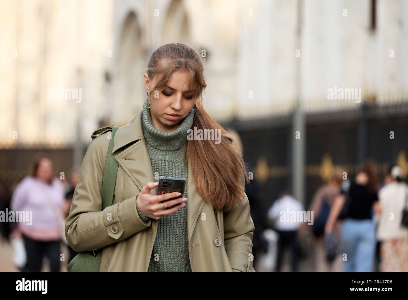 Girl walking with smartphone on a street on people background. Using mobile phone in city Stock Photo