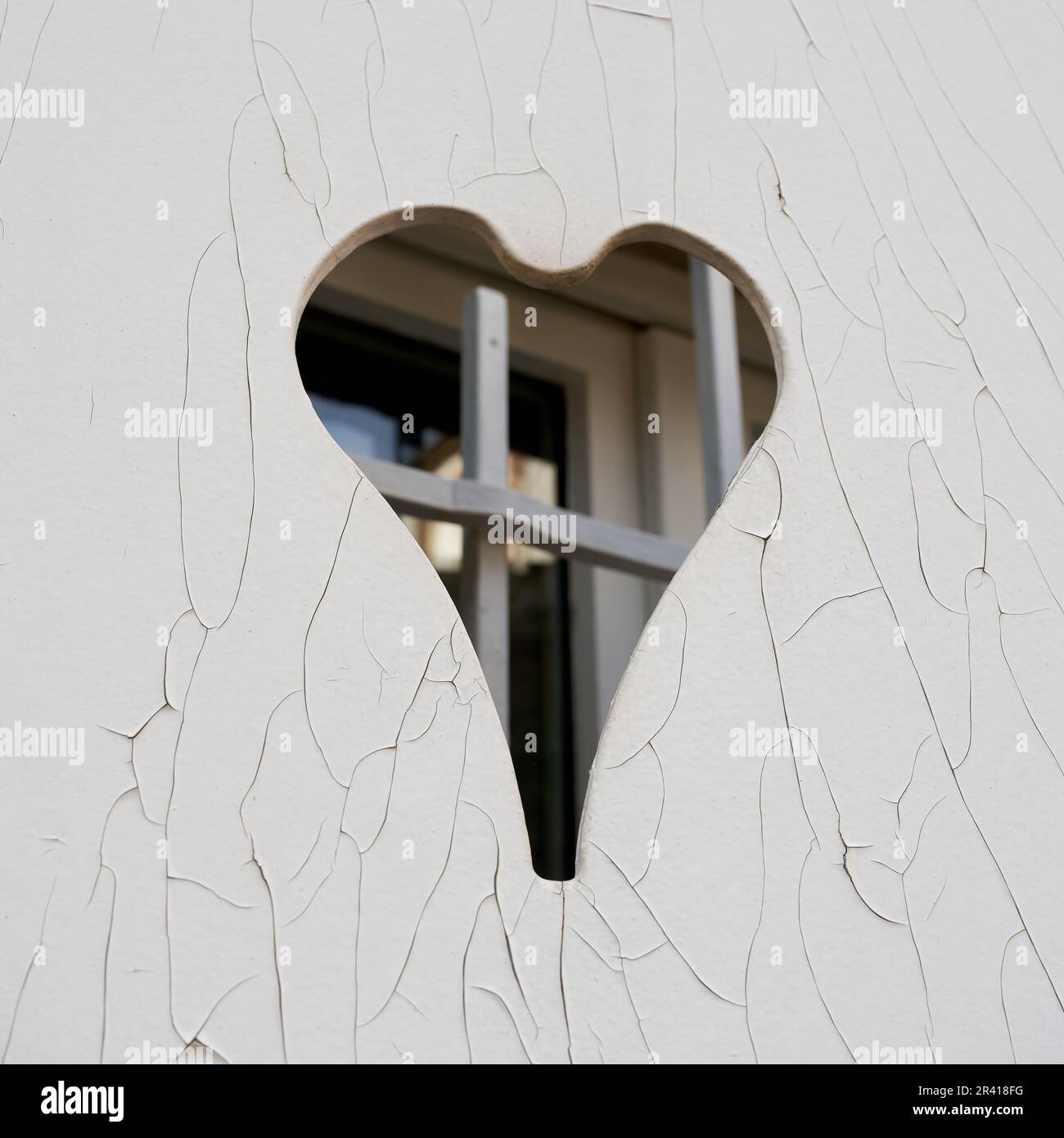 Closed white shutter with a heart-shaped opening and cracks in the paint in the old town of Colmar Stock Photo