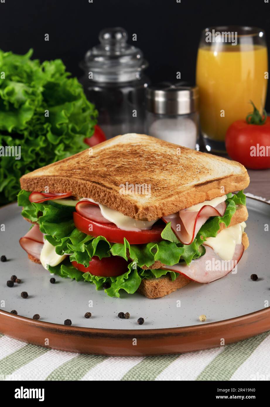 Sandwich with ham, cheese and vegetables on plate, on black background Stock Photo