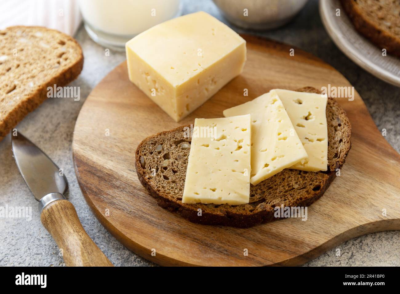 Healthy food concept, breakfast, superfood. Fresh whole grain bread with cheese and a glass of almond milk on stone table. Stock Photo