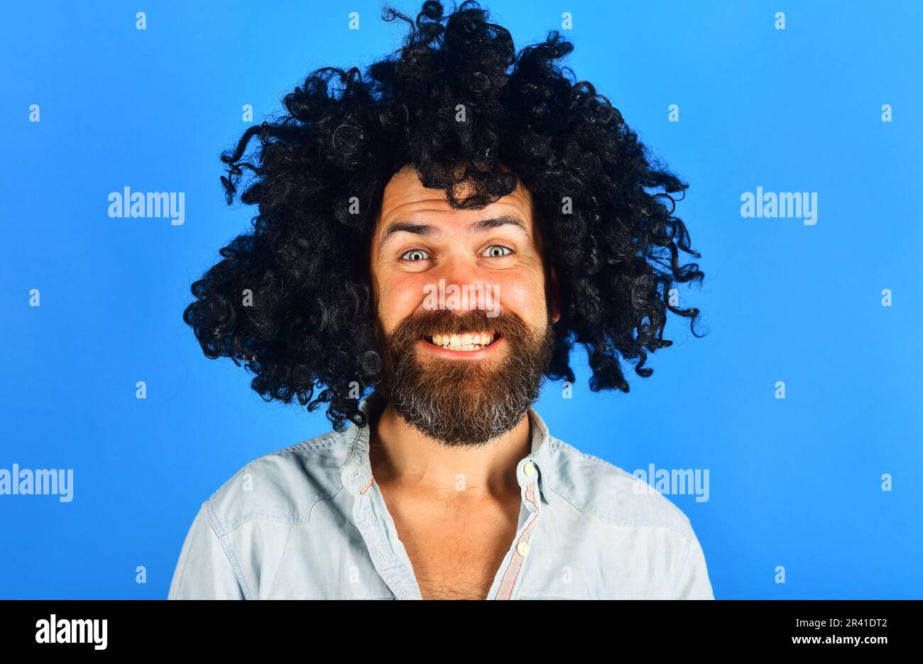 Bearded man in black wig. Happy man with beard and mustache in curly wig. Bearded hipster in black curly afro wig. Male in periwig. Party time. Barber Stock Photo