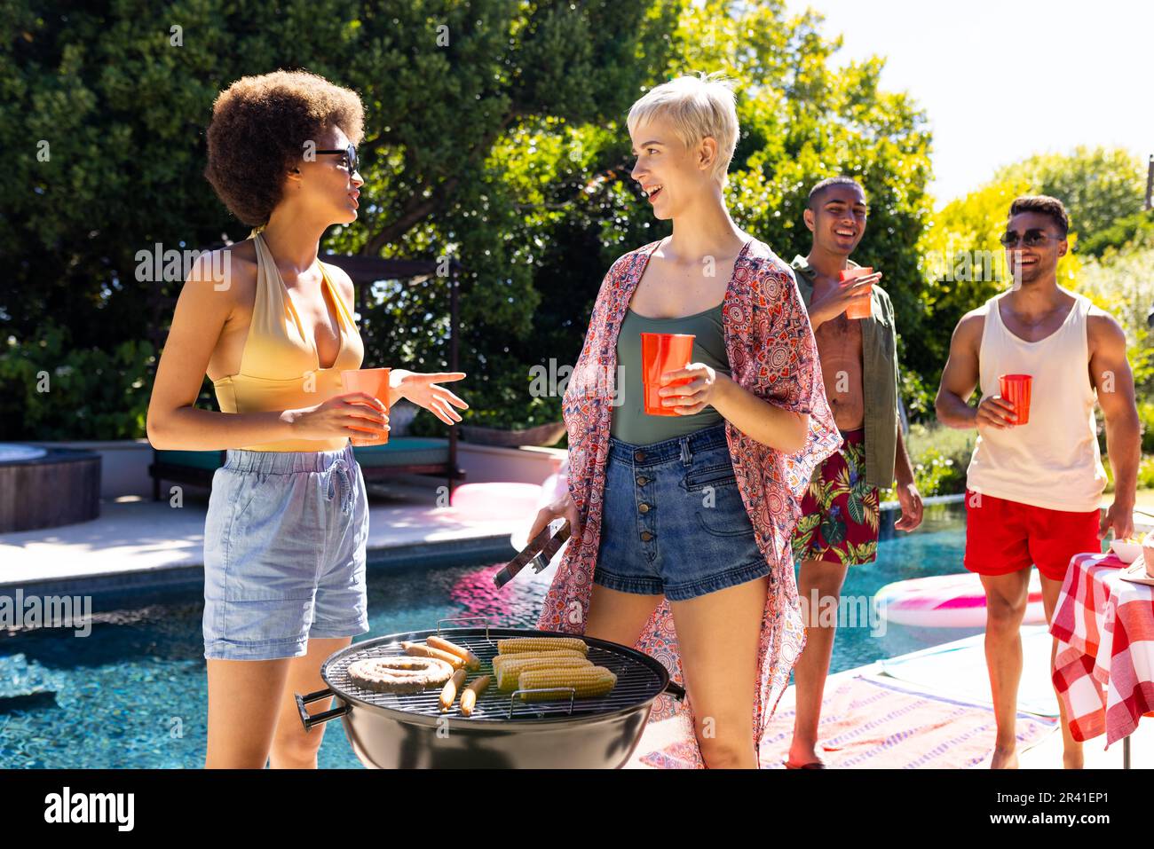 Happy diverse group of friends having pool party, barbecuing together ...