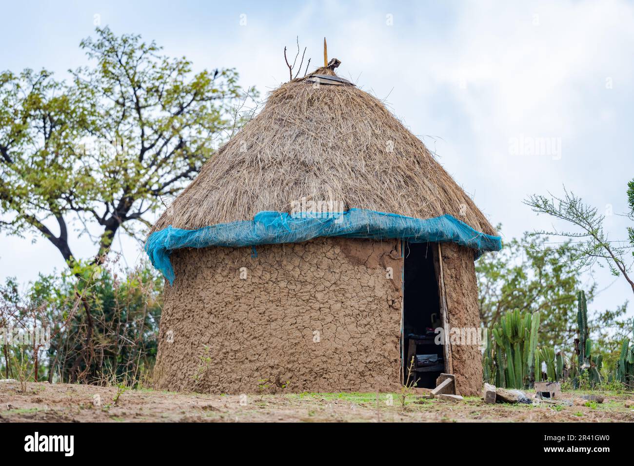 A traditional round mud hut with grass roof and clay wall in a remote village. Kenya, Africa. Stock Photo