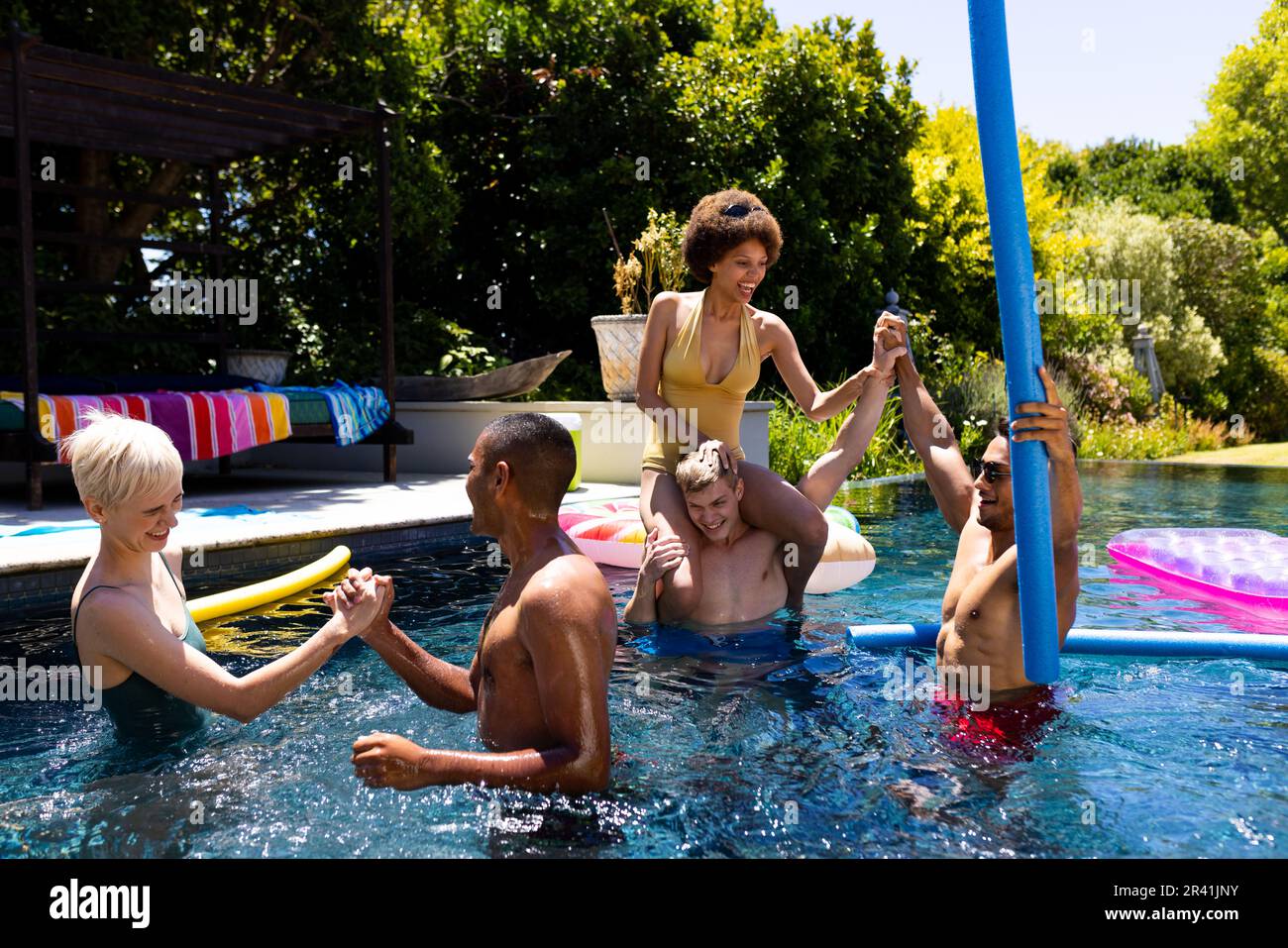 Happy diverse group of friends having pool party, playing in swimming ...