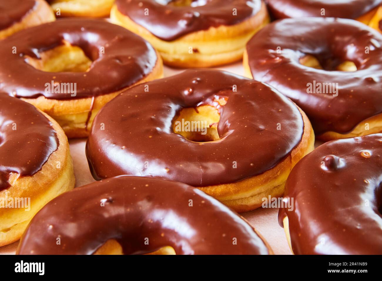 Side shot of half glazed yeast donuts with chocolate frosting on white tray background Stock