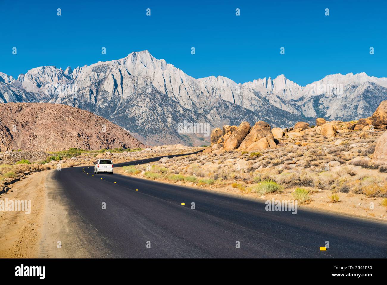 Car drives on Whitney Portal Road with the Sierra Nevada and Mount