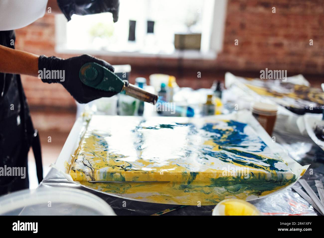 Woman uses a gas burner to draw in Fluid Art. Process of creating a