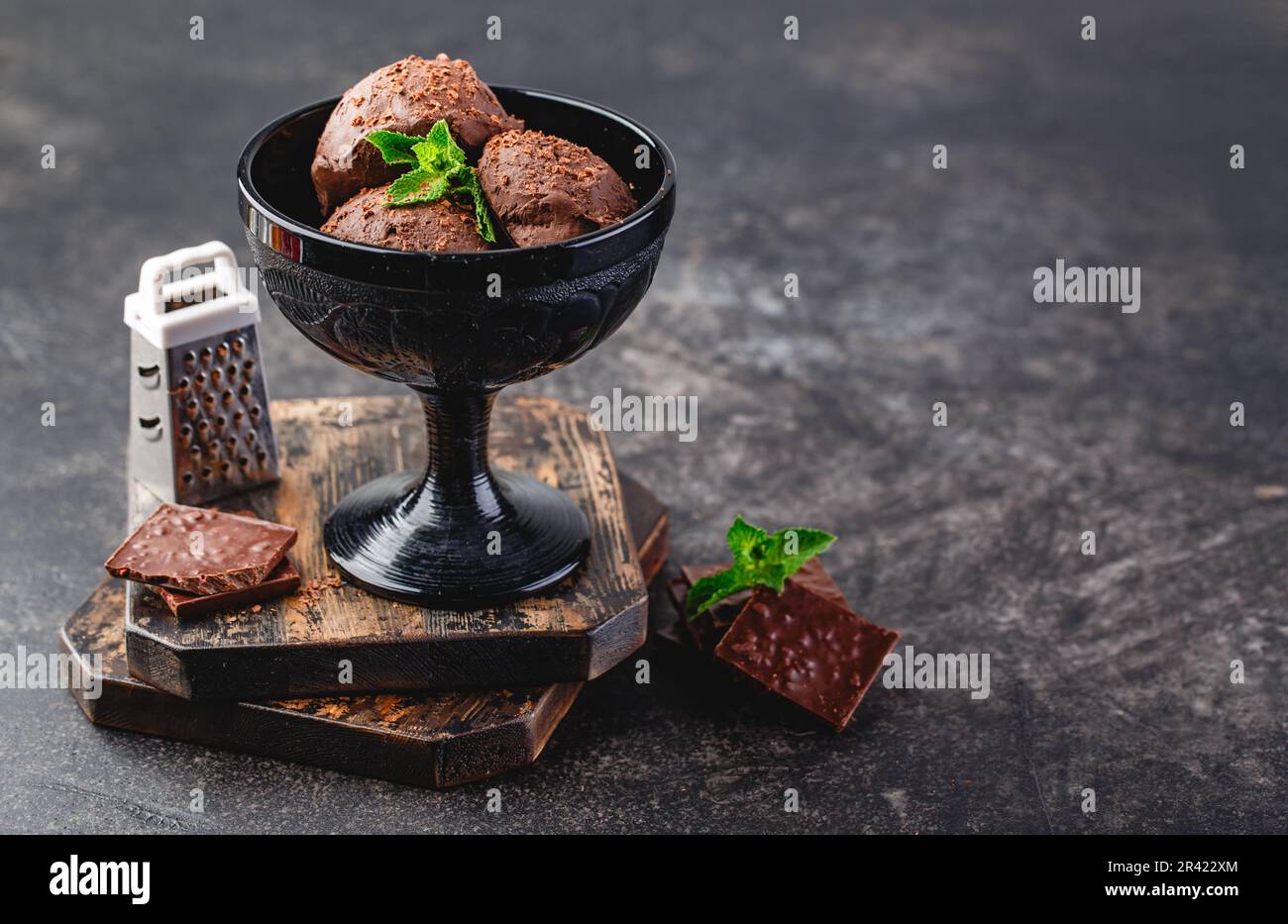 Three brown chocolate ice cream balls in black bowl on dark background Stock Photo