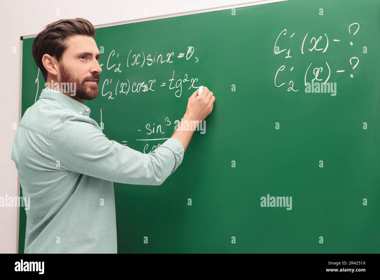 Mature teacher explaining mathematics at chalkboard in classroom Stock ...