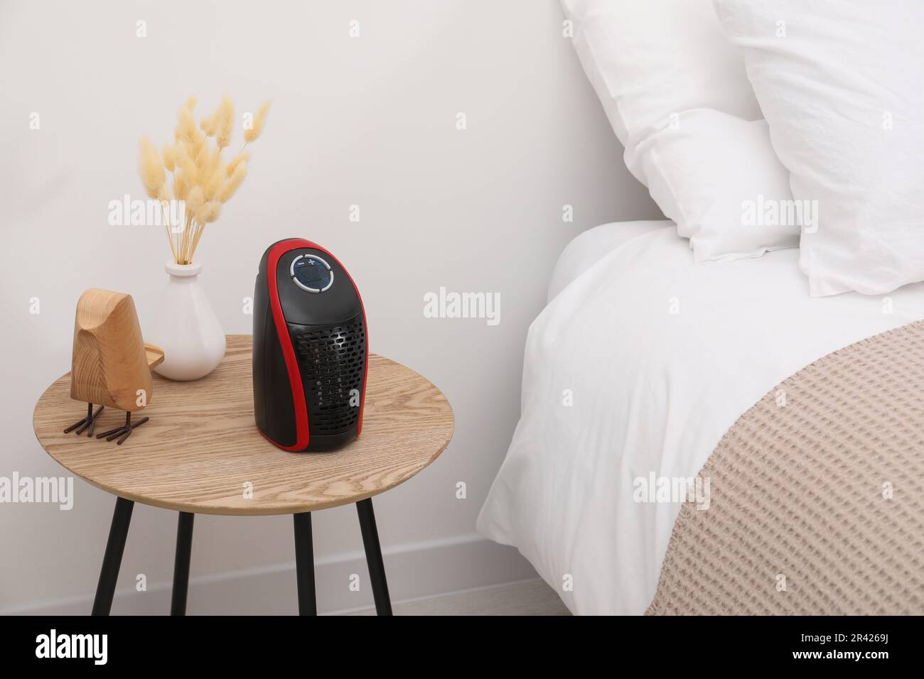 Modern compact electric heater on coffee table near bed indoors Stock Photo  - Alamy