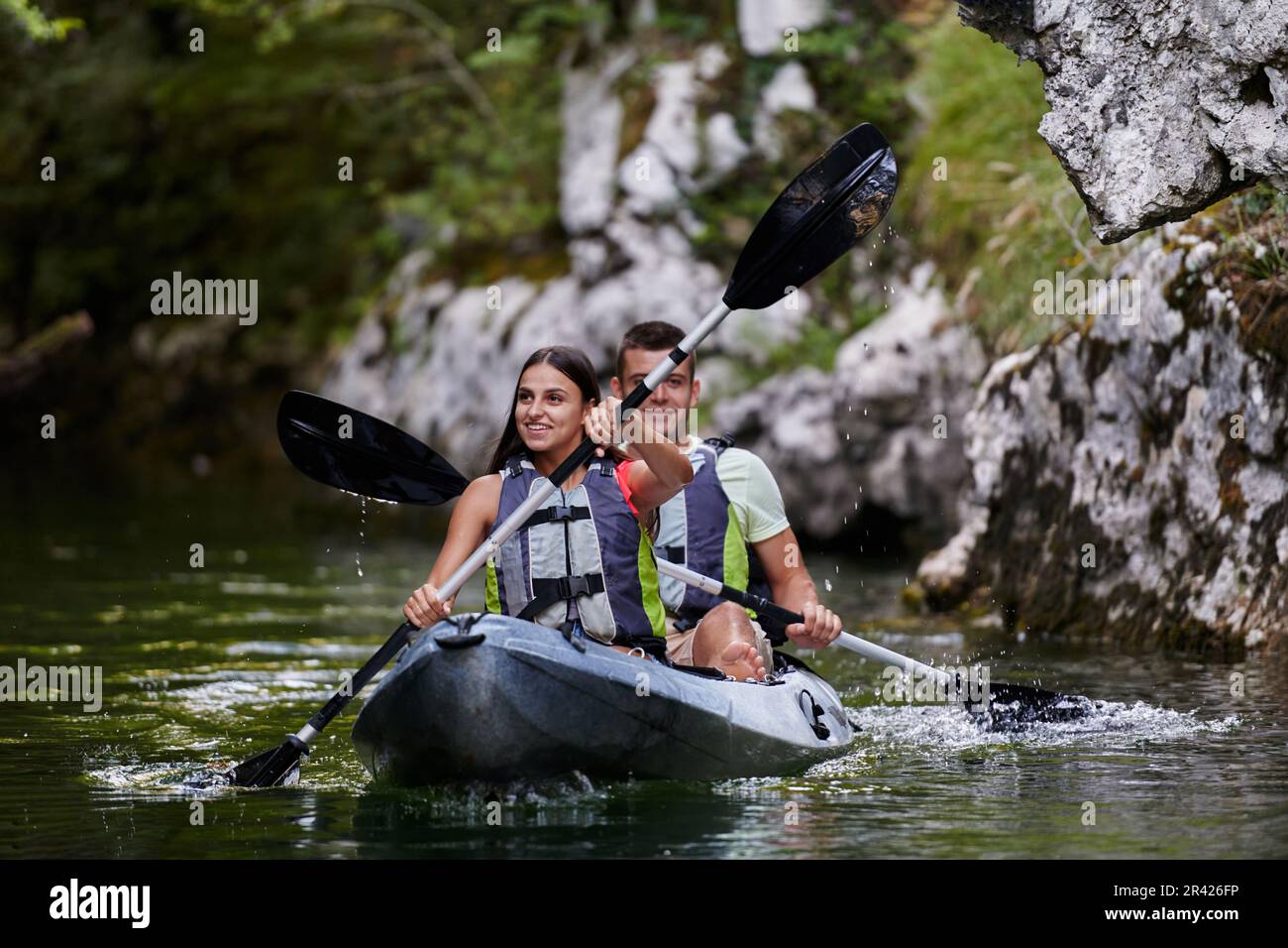 A young couple enjoying an idyllic kayak ride in the middle of a ...