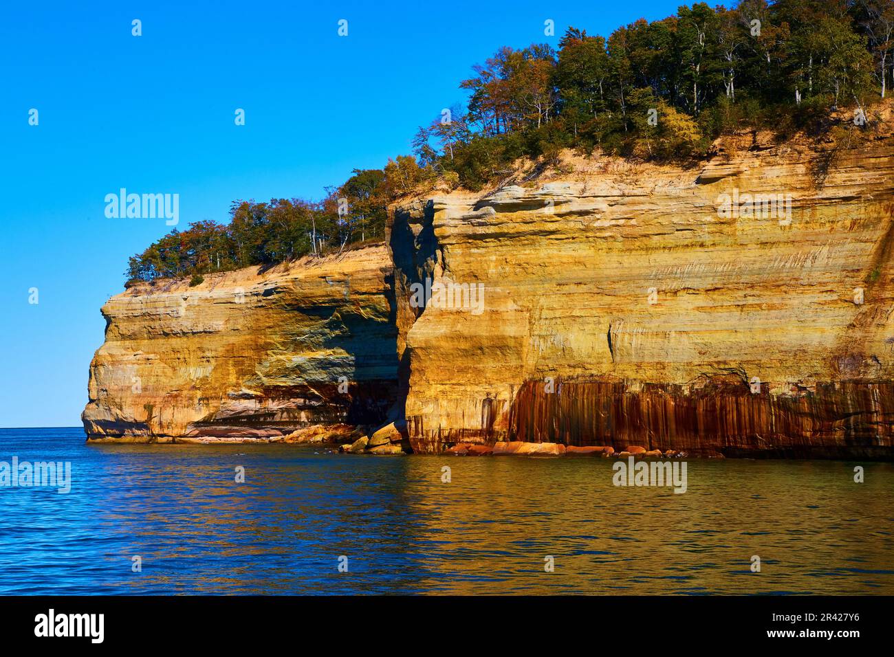 Cliff wall of pictured rocks at Michigan National Park with forest atop ...