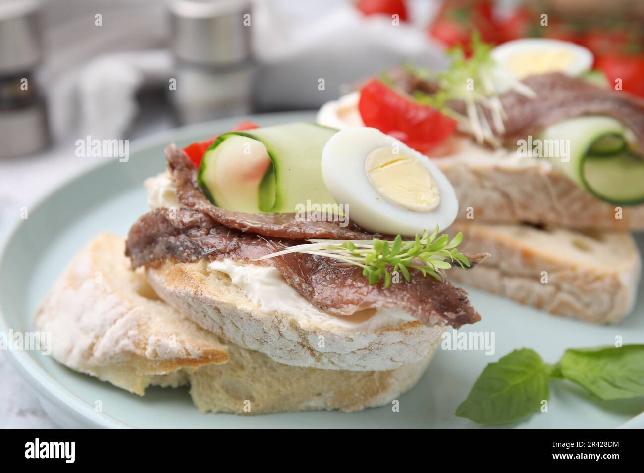 Delicious bruschettas with anchovies, tomato, cucumber, egg and cream cheese on plate, closeup Stock Photo
