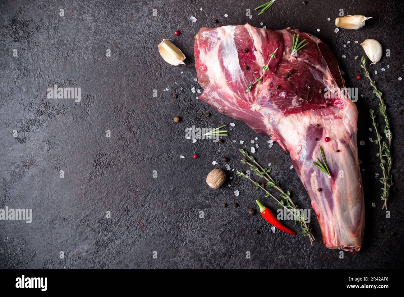 Raw fresh Lamb Meat shank and seasonings on black stone background Stock Photo