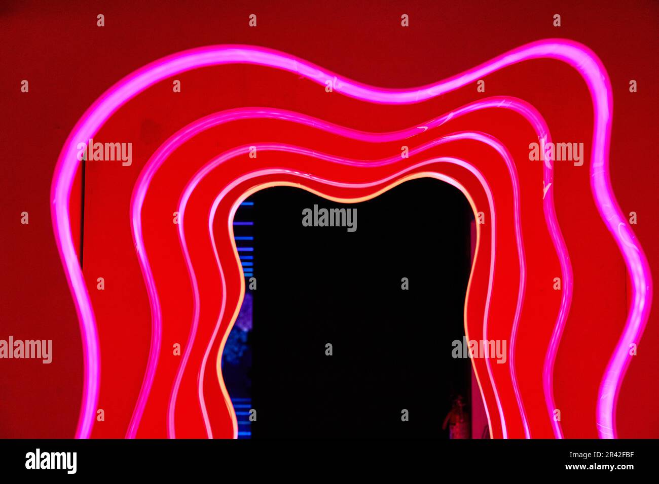 Red hallway of abstract red doors outlined in red neon lights and a
