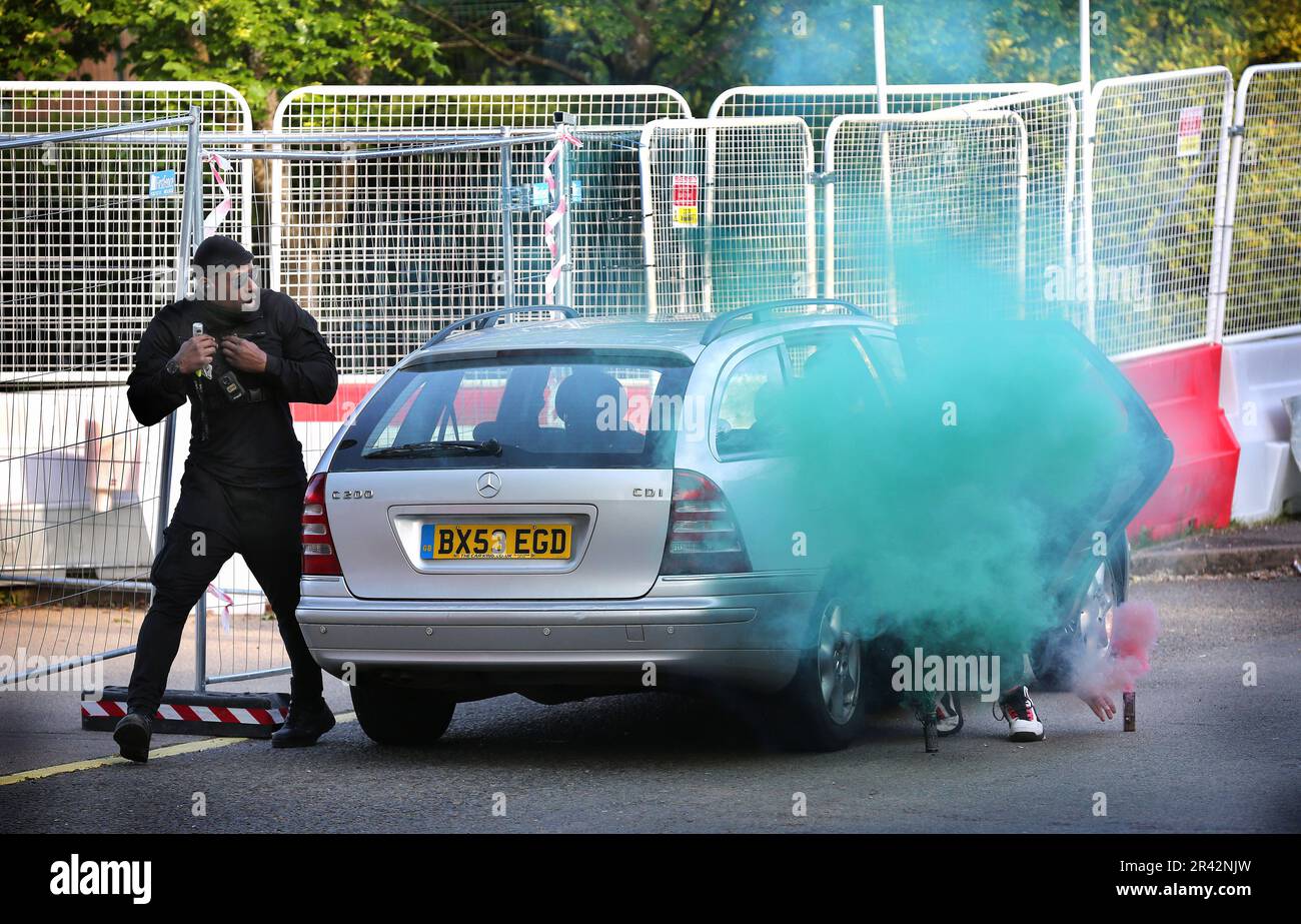 A security guard investigates a car that is blocking vehicle access to the factory of UAV Tactical Systems with coloured smoke billowing out from it. Protesters from Palestine Action have been protesting outside the UAV Tactical Systems factory in Leicester since May 1 2023. They say they will stay put until UAV Tactical Systems leaves. Police have issued a section 14 order that allows protesters a small official protest area opposite the factory to use. Any protests outside that area breach the order and will result in arrest. Protesters object to weapons produced in the UK by Israeli defence Stock Photo