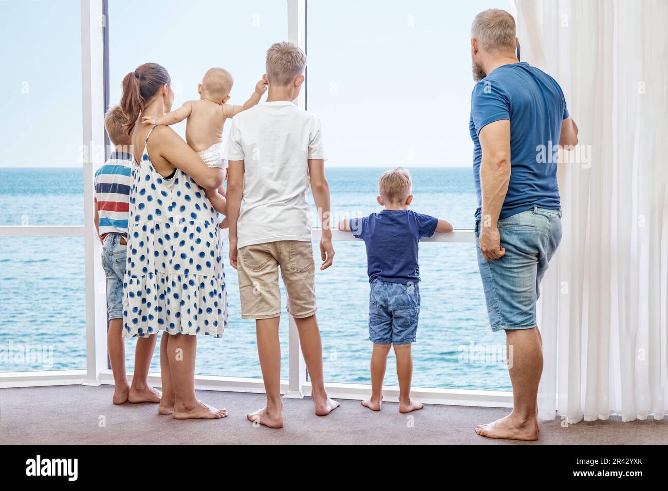 Parents and boys siblings enjoy spending together summer holidays on seaside. Father and mother take sons on holidays near azure sea Stock Photo