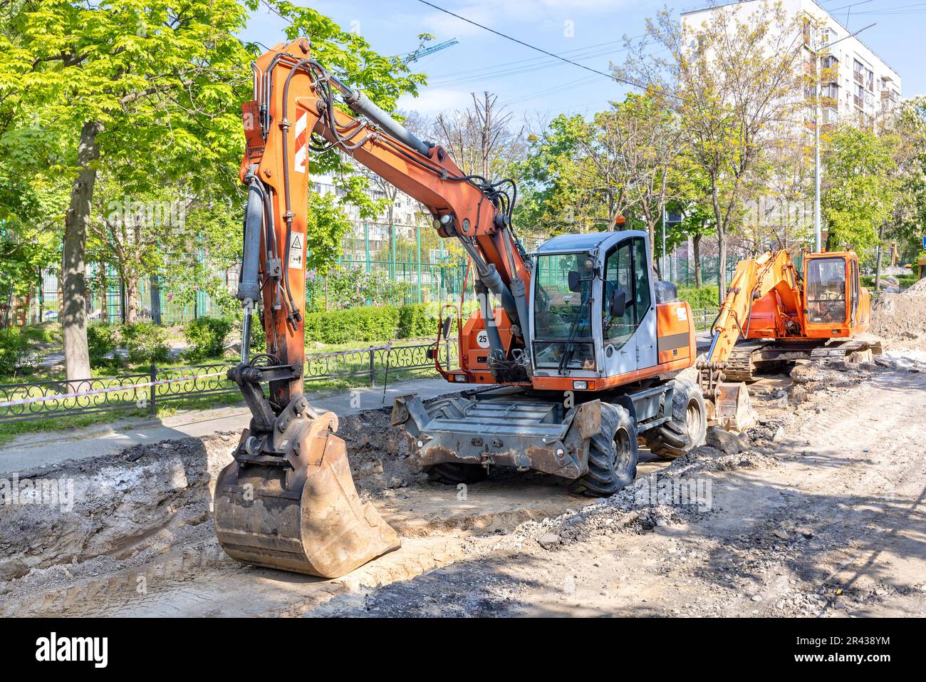Large wheeled and crawler excavators are parked in a trench dug in the ...
