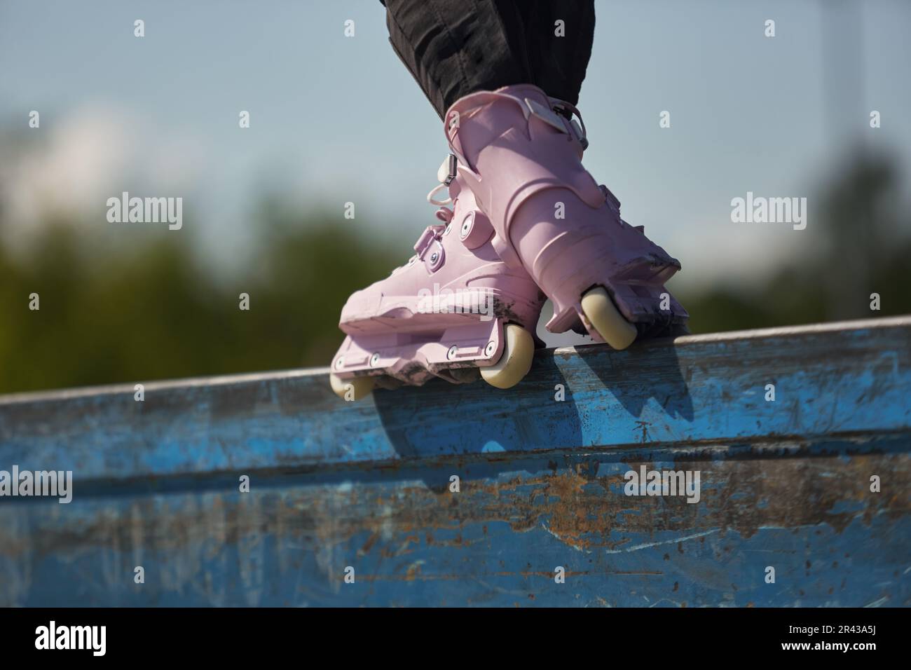 Skater girl grinding on a ledge in a skatepark. Female inline roller