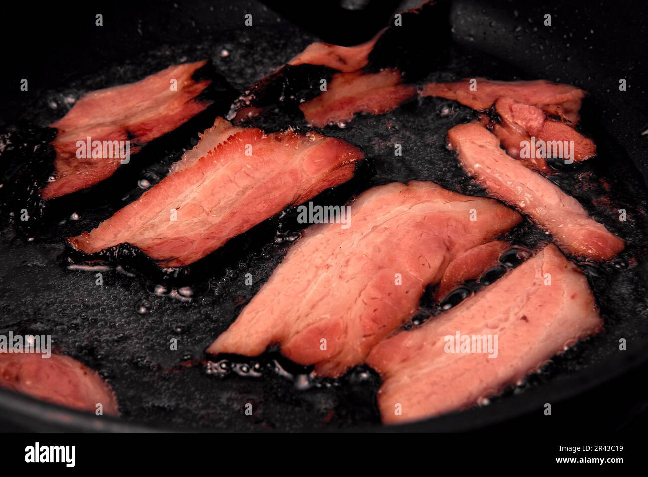 Frying Bacon Slices in a Pan. Crispy Pieces of Delicious Red Thin